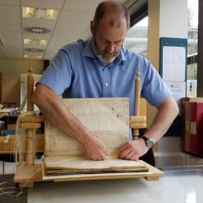 A conservator sewing the binding of an old book