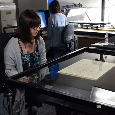 A woman looking at old documents underneath a piece of glass
