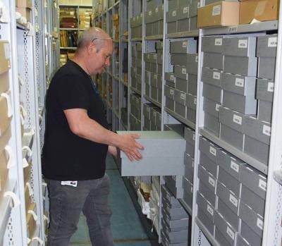 A member of NRO staff holding a box in the strongroom
